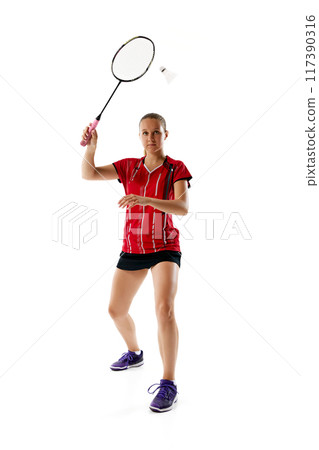 Competitive young woman standing ready to hitting shuttlecock in motion, repel enemy attack against white studio background. Competitive young woman standing ready to hitting shuttlecock in motion, repel enemy attack against white studio background. 117390316