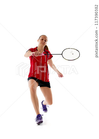 Young athletic woman playing badminton, in motion leaping to hit shuttlecock, attacking opponent against white studio background. Young athletic woman playing badminton, in motion leaping to hit shuttlecock, attacking opponent against white studio background. 117390382