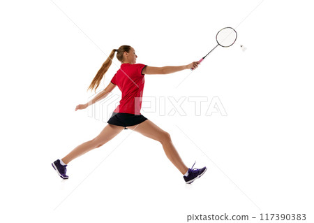 Side view photo of young woman in uniform with rocket, badminton player leaping to hits shuttlecock against white studio background. 117390383