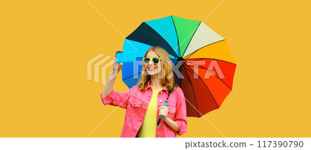 stylish happy smiling woman taking selfie with phone holds colorful umbrella on yellow background 117390790