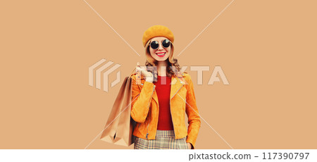 Autumn portrait of beautiful happy young woman with shopping bags in orange french beret on brown Autumn portrait of beautiful happy young woman with shopping bags in orange french beret on brown 117390797