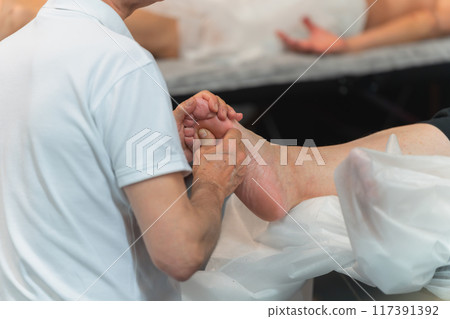 Foot massage for an overweight lady in a beauty salon 117391392