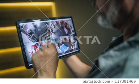 Professional installer watches security cameras in stylish office using tablet computer Professional installer watches security cameras in stylish office using tablet computer 117391469