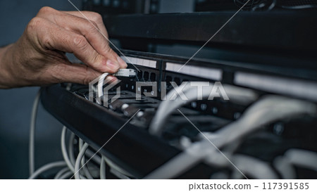 Male system administrator connects cables with server rack working in server room 117391585