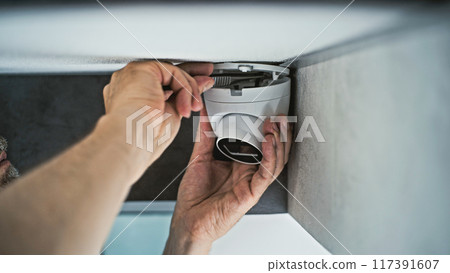 Male installer screws CCTV camera using screwdriver tool and adjusts the angle Male installer screws CCTV camera using screwdriver tool and adjusts the angle 117391607