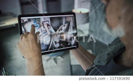 Male technician controls CCTV cameras in modern office using tablet computer Male technician controls CCTV cameras in modern office using tablet computer 117391690