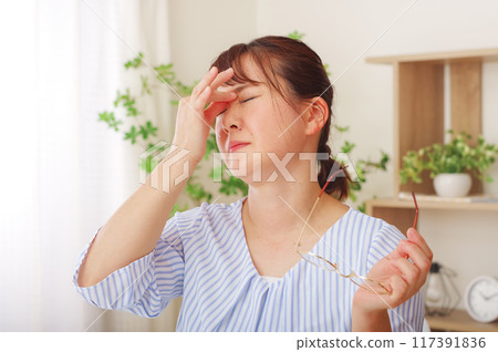 Middle-aged woman holding her eyes due to eye trouble Middle-aged woman holding her eyes due to eye trouble 117391836