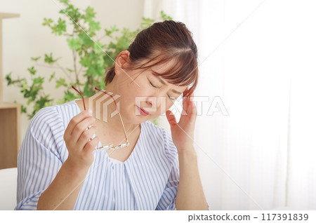 Middle-aged woman holding her eyes due to eye trouble 117391839