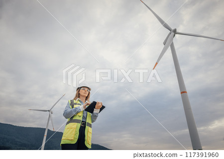 A female engineer inspects a wind turbine at a renewable energy facility, highlighting her key role in advancing sustainable practices and technological innovation in the industry 117391960
