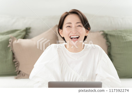 Living room, middle-aged woman, computer, smiling 117392274
