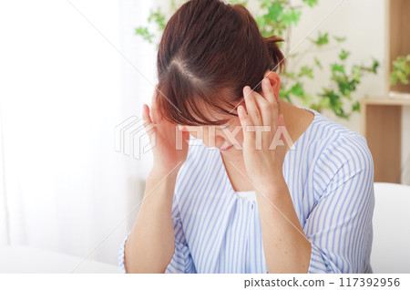 Senior woman with a headache holding her temples 117392956