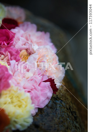 A flower water basin with colorful flowers floating in it 117393044