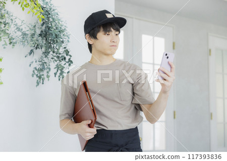 A young male cafe attendant looking at his smartphone A young male cafe attendant looking at his smartphone 117393836
