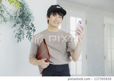 看智慧型手機的年輕男性咖啡館職員 117393838