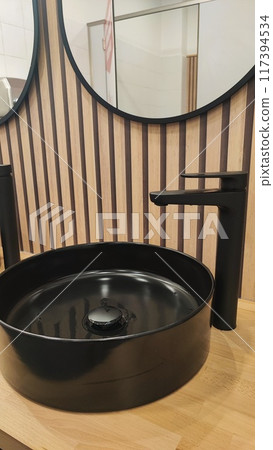 Hygiene concept in public places - Black stylish sink and mirror in a public modern restroom Hygiene concept in public places - Black stylish sink and mirror in a public modern restroom 117394534