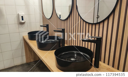 Hygiene concept in public places - Black stylish sink and mirror in a public modern restroom 117394535