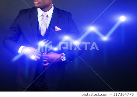 A man in a suit is wearing a watch and is adjusting his tie 117394776