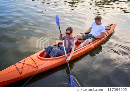 the couple in love kayaking on the river at sunset 117394995