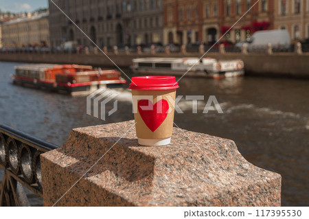 Brown cup of natural coffee with red heart on bridge near embankment of Fontanka river in St. Petersburg Brown cup of natural coffee with red heart on bridge near embankment of Fontanka river in St. Petersburg 117395530