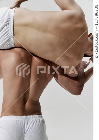 Close up, rear view photo of wrestler confidently lifts his opponent, capturing essence of strength against warm grey background. Close up, rear view photo of wrestler confidently lifts his opponent, capturing essence of strength against warm grey background. 117396239