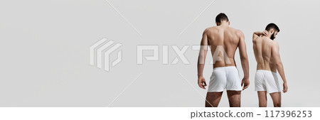 Banner. Rear view photo of men in white underwear posing shoes his healthy back against warm grey background with negative space. 117396253