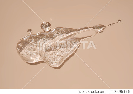 A drop of lubricant or cosmetic gel on a beige background. A drop of lubricant or cosmetic gel on a beige background. 117396336
