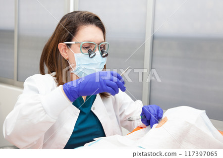 Dermatologist carrying out a skin biopsy on the face of a senior adult patient 117397065