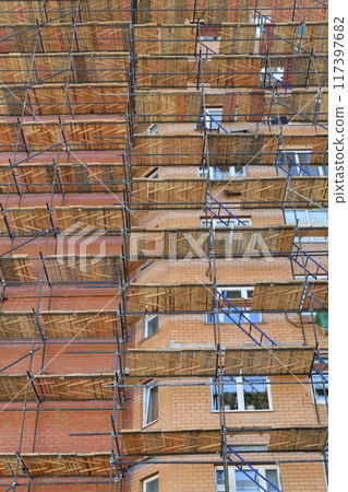 A brick house under construction with wooden scaffolding 117397682