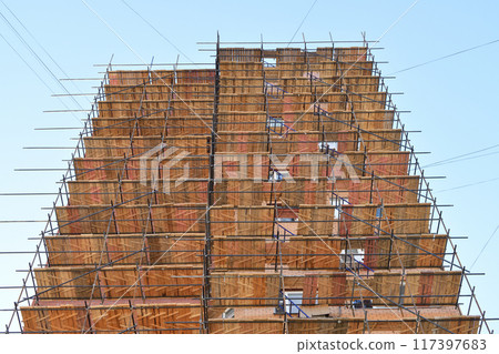 A brick house under construction with wooden scaffolding 117397683