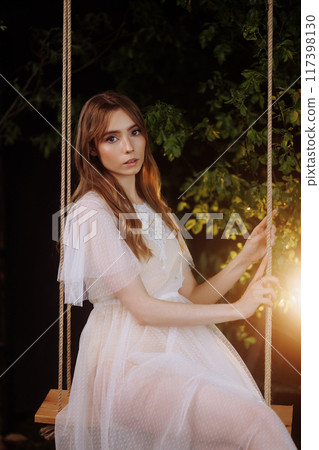 Elegant woman on wooden swing. Elegant woman on wooden swing. 117398130