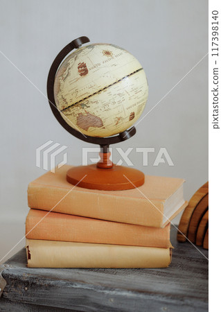 A globe sits on top of a stack of books 117398140