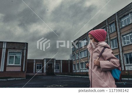Little girl in pink coat with backpack in disadvantaged area goes to school Little girl in pink coat with backpack in disadvantaged area goes to school 117398142