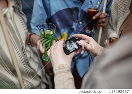 Group of people socializing, holding drinks while someone is taking a picture with a compact digital camera during gathering Group of people socializing, holding drinks while someone is taking a picture with a compact digital camera during gathering 117398487