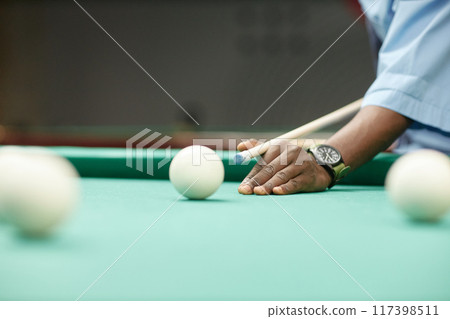 Hand holding billiard cue aiming at cue ball on pool table with other balls spread around creating an engaging game setup Hand holding billiard cue aiming at cue ball on pool table with other balls spread around creating an engaging game setup 117398511