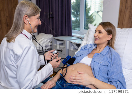 Long-haired female doctor measuring blood pressure to a pregnant woman 117399571