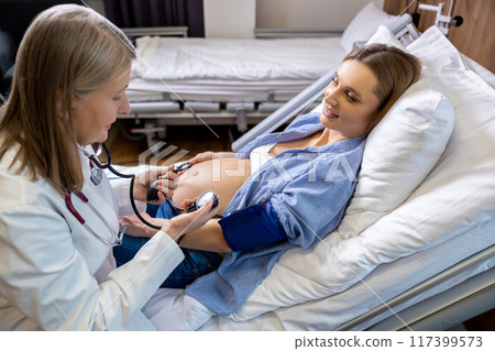 Doctor measuring blood pressure of a pregnant woman on third trimester 117399573