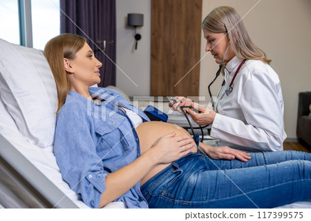 Doctor measuring blood pressure of a pregnant woman on third trimester 117399575