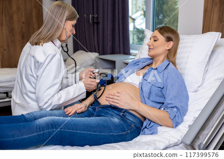 Doctor measuring blood pressure of a pregnant woman on third trimester 117399576