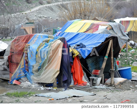 Color photo of makeshift tents made from colorful blankets in a refugee camp. 117399958
