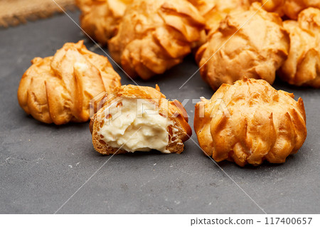 Delicious cream-filled profiteroles arranged on a dark slate surface, perfect for dessert lovers 117400657