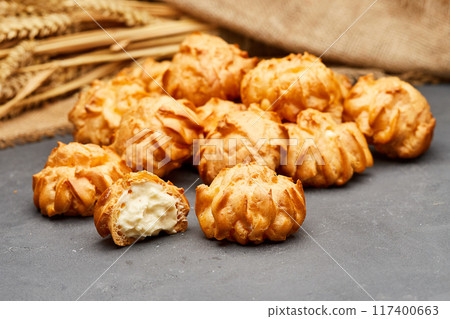 Delicious cream-filled profiteroles arranged on a dark slate surface, perfect for dessert lovers Delicious cream-filled profiteroles arranged on a dark slate surface, perfect for dessert lovers 117400663