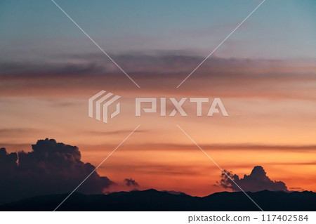 Summer sunset, cumulonimbus clouds and mountain silhouettes, light tones 117402584