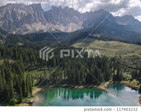 Stunning mountain landscape with an emerald lake surrounded by a lush pine forest. Lake Carezza Stunning mountain landscape with an emerald lake surrounded by a lush pine forest. Lake Carezza 117403232