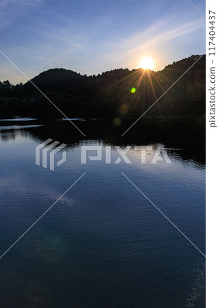 Summer at Nunome Dam in the eastern part of Nara City. Evening view towards the dam lake. The surface of the dam lake illuminated by the setting sun on the opposite bank. 117404437