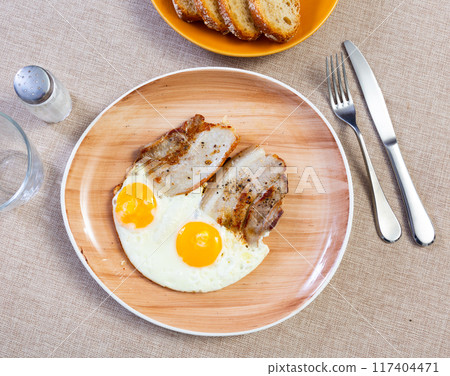 Appetizing breakfast with scrambled eggs and juicy bacon closeup Appetizing breakfast with scrambled eggs and juicy bacon closeup 117404471