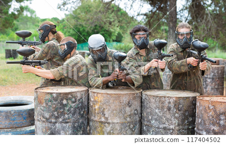 Group of paintball players aiming and shooting with guns Group of paintball players aiming and shooting with guns 117404502