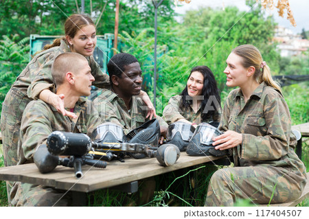 Smiling friends chatting after successful paintball match Smiling friends chatting after successful paintball match 117404507
