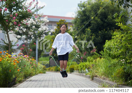 盛夏的某一天，一名小學生在住宅區的街道上歡快地跳繩。 117404517