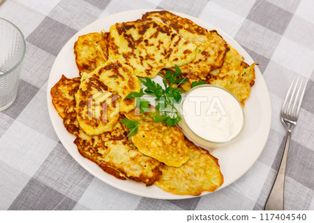 On plate are vegetable pancakes made from grated zucchini On plate are vegetable pancakes made from grated zucchini 117404540