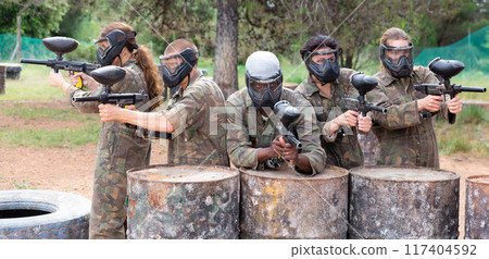 Group of paintball players aiming and shooting with guns Group of paintball players aiming and shooting with guns 117404592